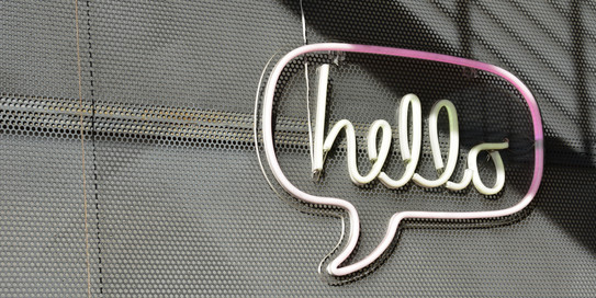 Neonreklame in Form einer Sprechblase, im Inneren steht das Wort „hello“