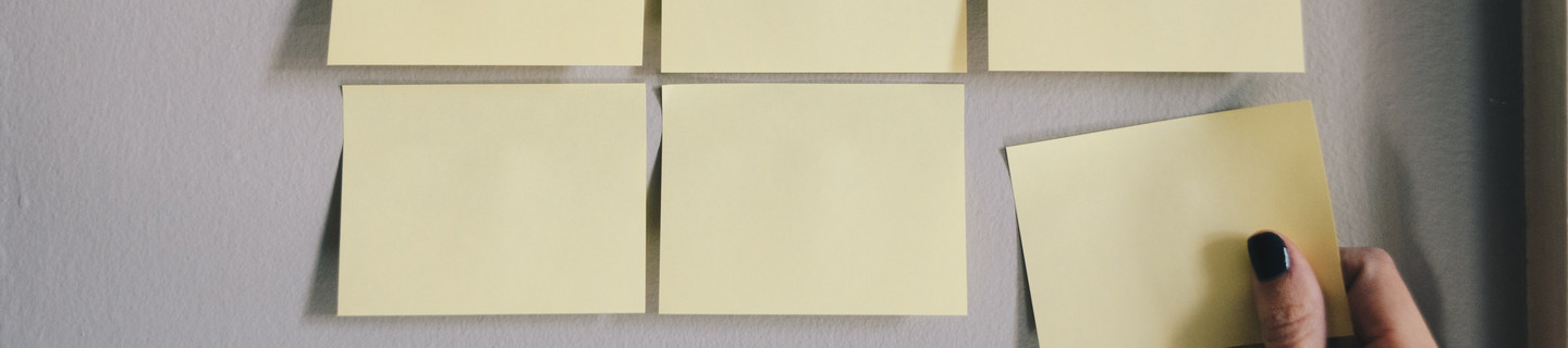 Gelbe Haftnotizzettel, die in drei Reihen à drei Zettel auf eine weiße Fläche geklebt sind