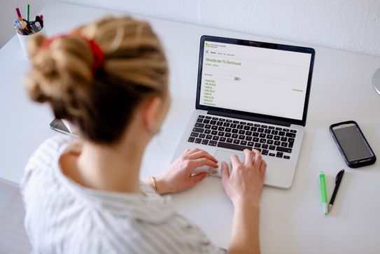 Umgang mit digitalen Medien/Moodle Foto einer Frau, die auf einen Laptop blickt.